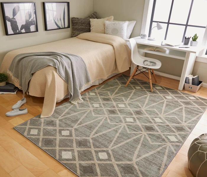 Small, stylish bedroom with a gray rug, neutral bedding, a white desk, and a window with blinds.