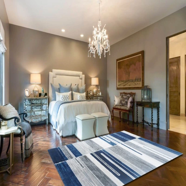 Stylish bedroom featuring a bold, graphic rug, neutral bedding, and mirrored furniture.